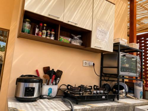 a kitchen counter with a stove and a microwave at Wavez Lombok Hostel in Selong Belanak