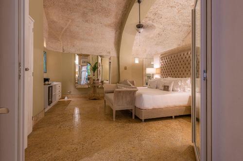 a large bedroom with a bed and a chair at Hotel Casa del Gobernador in Cartagena de Indias