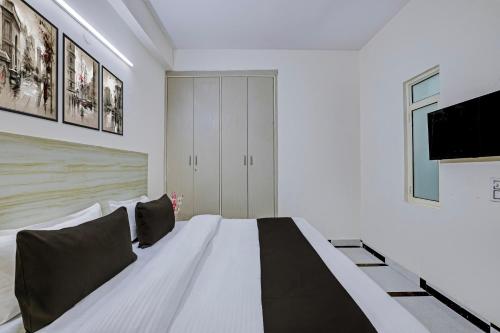 a bedroom with a bed and a tv on the wall at Hotel O DLF Phase 1 Metro Station Gurugram in Gurgaon