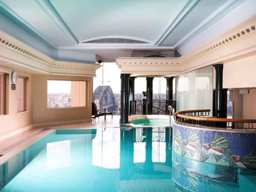 a swimming pool in a building with a view at The Sebel Quay West Suites Sydney in Sydney