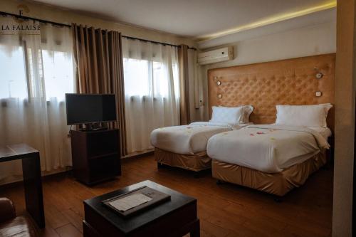 a hotel room with two beds and a television at Hotel Résidence La Falaise in Douala
