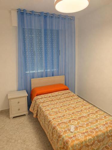 a bedroom with a bed and a window with blue curtains at Villa Nasra in Los Altos
