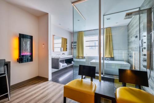 a bathroom with a yellow chair and a sink and a tub at Hôtel Ô Laval in Laval