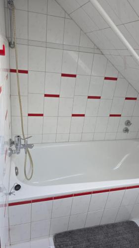 a bathroom with a white tub and red and white tiles at Kurzzeitvermitung Angelov in Hameln