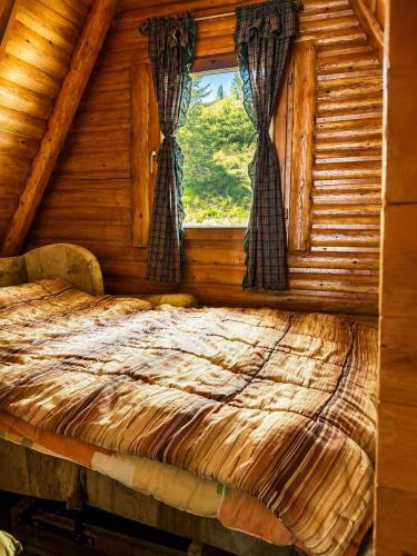a bed in a log cabin with a window at Komovi Sky House in Andrijevica