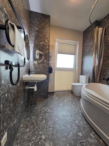 a bathroom with a sink and a tub and a toilet at Synet CoLiving in Mažeikiai