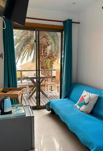 a living room with a blue couch and a balcony at Hostal Maitencillo Norte in Maitencillo