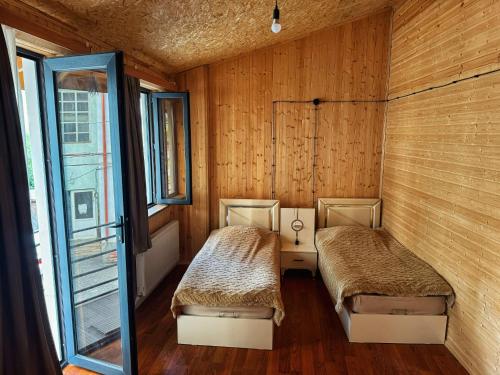 two beds in a room with wooden walls and windows at Casa nostra in Ambrolauri