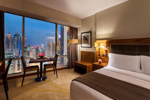 a hotel room with a bed and a desk with a window at InterContinental Doha The City by IHG in Doha