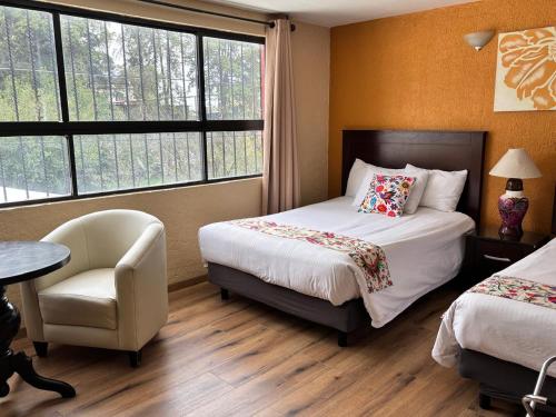 a hotel room with two beds and a chair at Hotel Finca Las Hortensias in Tepotzotlán