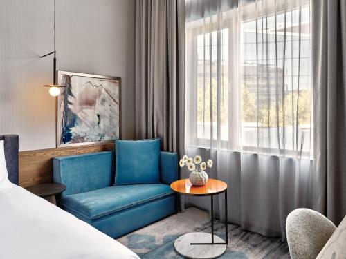 a hotel room with a blue chair and a table at Crowne Plaza Sofia by IHG in Sofia