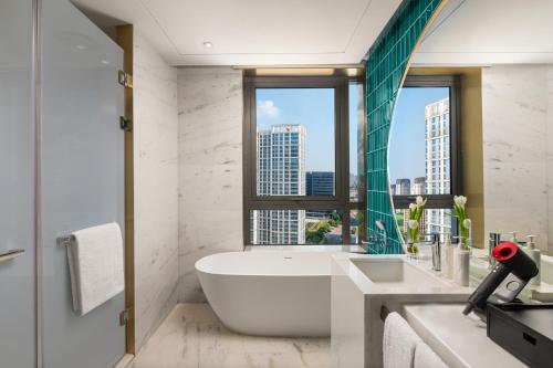 a bathroom with a bath tub and a window at HUALUXE Shanghai Changfeng Park by IHG in Shanghai