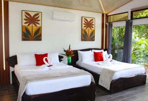 two beds sitting in a room with windows at Pino Lodge, Río Celeste in Bijagua