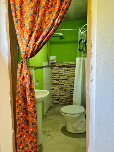 a bathroom with a toilet and a shower curtain at Aroeira Suite in Conceição da Barra