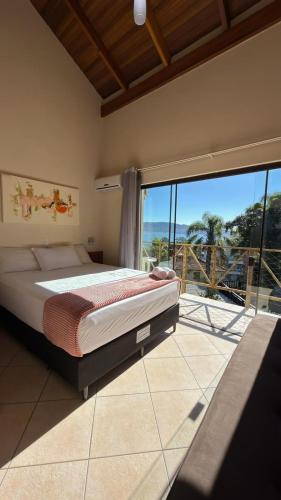 a bedroom with a bed and a large window at Pousada Aquarela de Bombinhas in Bombinhas