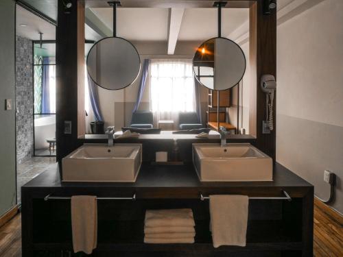 a bathroom with two sinks and two mirrors at Casa Pepe in Mexico City