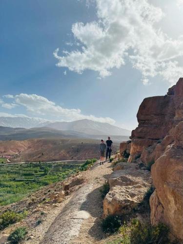 two people walking down a dirt road on a mountain at Gîte flilou in Midelt