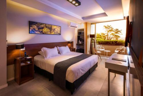 a hotel room with a large bed and a balcony at Pinares Panorama Suites, Spa & Convention Center in Villa Carlos Paz