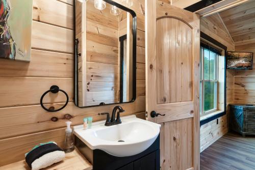 a bathroom with a sink and a mirror at Smoky Mountain Cabin, Sleeps 12, 2 Kitchens & Hot Tub in Pigeon Forge