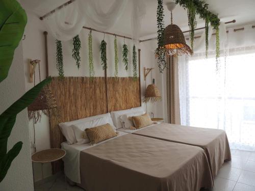 a bedroom with a bed with white sheets and plants at LOS NAREJOS Hotel in Los Alcázares