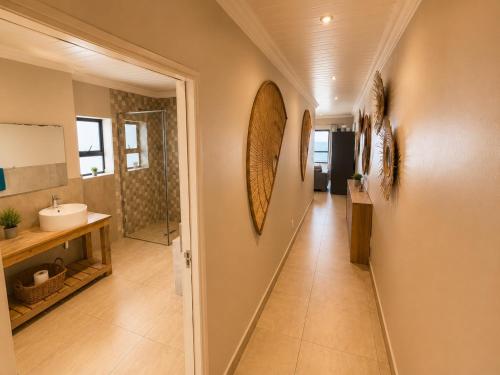 a hallway of a bathroom with a sink and a mirror at White Sands Self-catering units in Wilderness