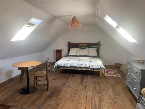 a bedroom with a bed and a table and skylights at Ti Bihan in Plouguerneau