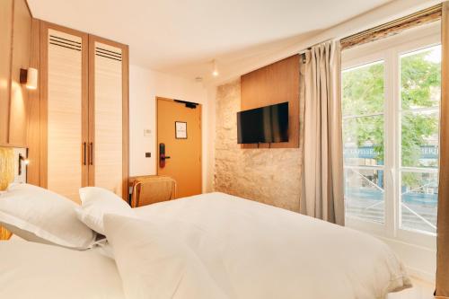 a bedroom with a large white bed and a window at Hotel Murmures Notre-Dame in Paris