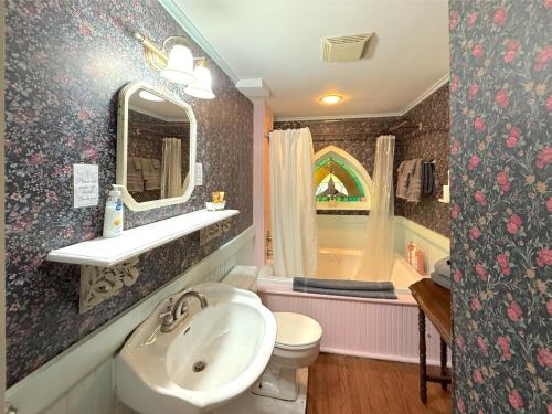 a bathroom with a sink and a toilet and a tub at Cricket Cottage in Eureka Springs
