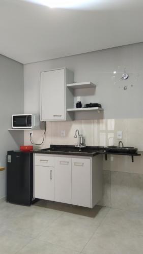 a kitchen with white cabinets and a black refrigerator at Studio 1 in Jundiaí