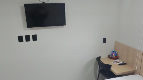 a room with a table and a television on the wall at GoldMen Express Cianorte in Cianorte