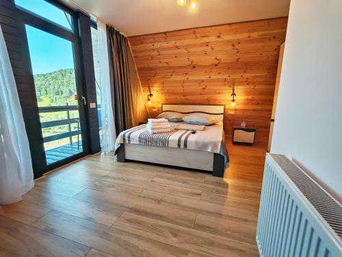 a bedroom with a bed and a large window at Cabana Magia Muntelui in Prisaca Dornei