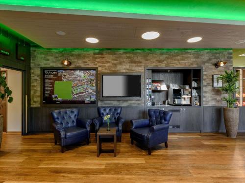 a waiting room with chairs and a flat screen tv at ibis Styles Tuebingen in Tübingen