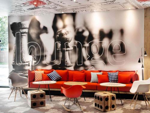 a living room with a red couch in front of a wall at Ibis Gdansk Stare Miasto in Gdańsk