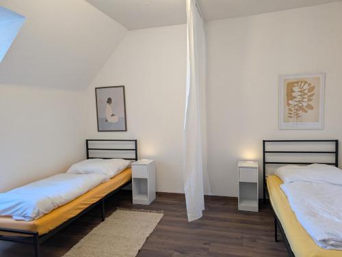 two beds in a room with white walls and wood floors at Crew Base Zeltweg in Zeltweg