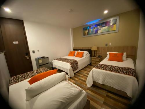 a hotel room with two beds and a couch at Hotel Ucla Center in Valledupar