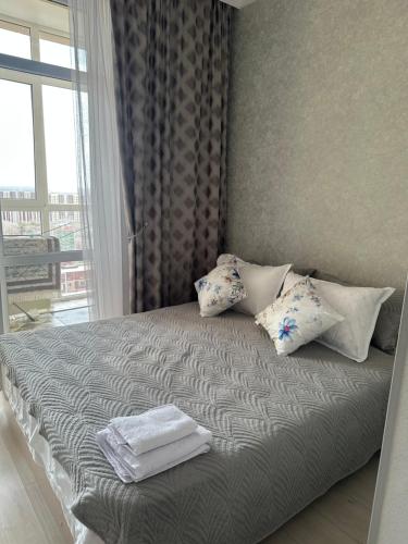 a bedroom with a bed with pillows and a window at Dostar Apartments in Karagandy