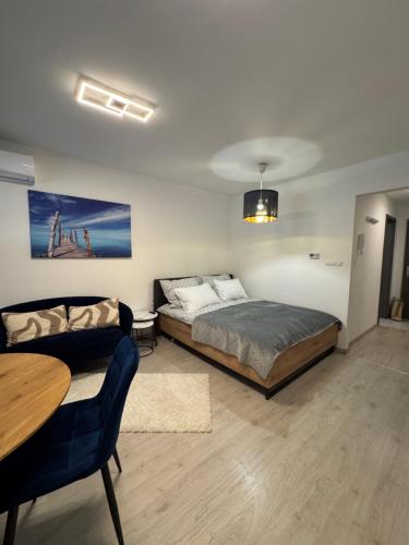 a bedroom with a bed and a couch and a table at Azzurro Room in Zalaegerszeg