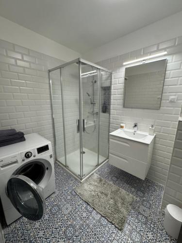 a bathroom with a shower and a washing machine at Azzurro Room in Zalaegerszeg