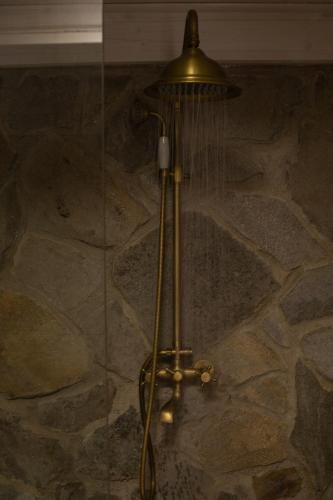 a shower stall with a shower head on a stone wall at Domek na wyłączność w Otulinie Ojcowskiego Parku Narodowego in Wola Kalinowska
