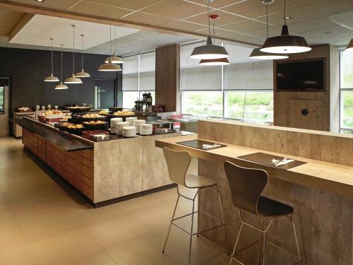 a kitchen with a counter with bar stools in it at ibis Osasco in Osasco