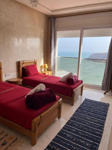 two beds in a bedroom with a view of the ocean at Goldenbeachhouse in Mirleft