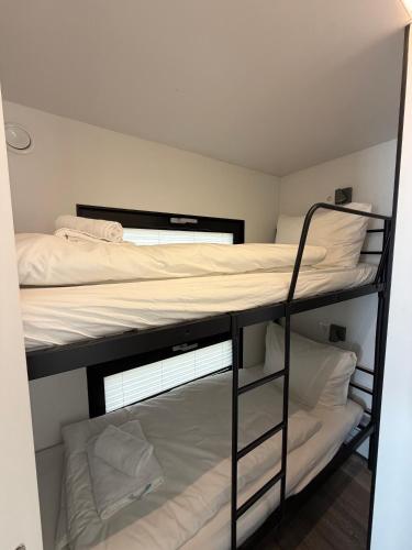 a bedroom with two bunk beds with white sheets at Design-Hausboot am Rheinsteig in Lorch am Rhein