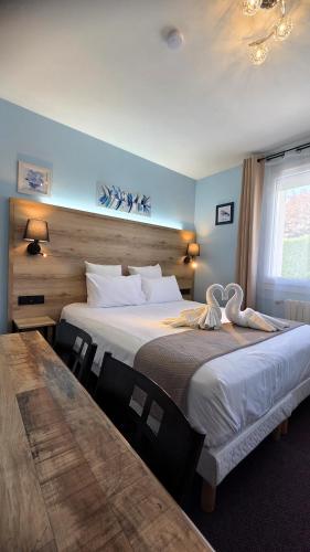 a hotel room with two beds and a table at Hôtel Le Pommeil in Guéret