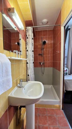 a bathroom with a sink and a shower and a tub at Hôtel Le Pommeil in Guéret
