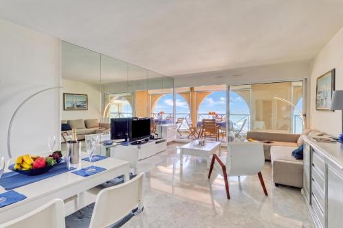 a living room with white furniture and a large mirror at Victoria Palace Elegant Apt with Terrace in Menton