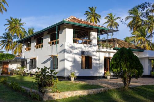 a white house with palm trees in the background at Don Padris Estate Bungalow in Tangalle