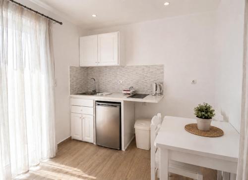 a white kitchen with a sink and a table at Cyclades Blue in Ornos
