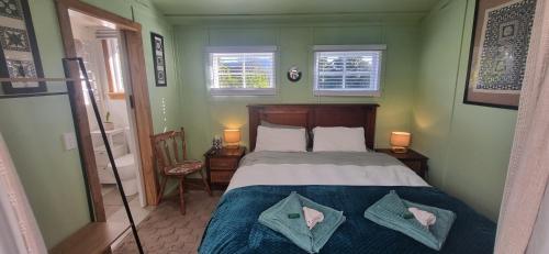 a bedroom with a large bed with two pillows at Rameka Chalet in Takaka
