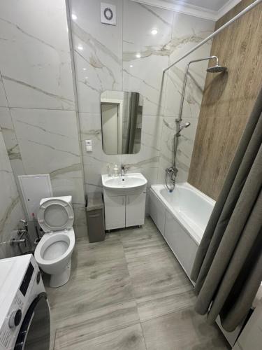 a bathroom with a toilet and a tub and a sink at Dostar Apartments in Karagandy