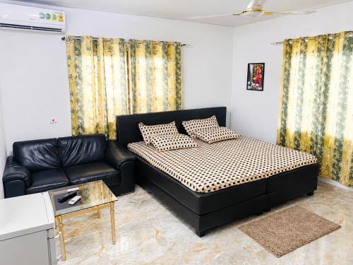 a bedroom with a black bed and a couch at Big Papa Hotel in Amasaman